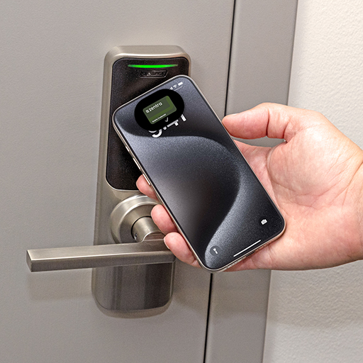 A person uses a smartphone with the Zentra app to unlock a Schlage smart lock, illustrating seamless and secure multifamily property access.